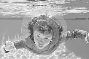 Boy swim and dive underwater. Under water portrait in swim pool. Child boy diving into a swimming pool.