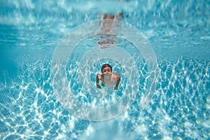 Boy swim and dive underwater. Under water portrait in swim pool. Child boy diving into a swimming pool.