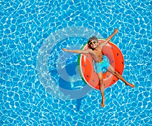 Boy swim in pool on inflatable ring from above