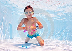 Boy swim underwater take toys in pool with googles