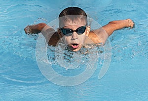 Boy swimmer swimming butterfly stroke in pool. Young athlete swim in swimming pool, training, competition, water sports