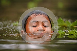 Boy swimming in the cannal near the Damnoen Saduak Floating Market