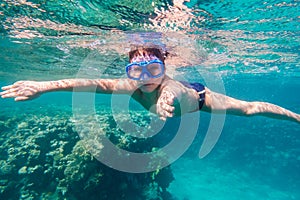 Boy in swimming mask dive in Red sea near coral reef