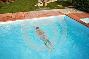 Boy swimming in the open pool in summer