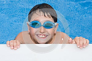 Boy swimming in the pool with goggles and a big g