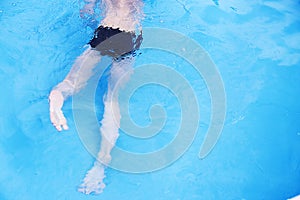 Boy swims in the pool. boy learning to swim.