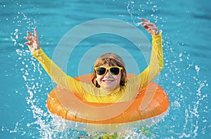 Boy swims in pool with float. Swimming, summer vacation. Child swim in pool on inflatable ring. Kid with inflatable ring