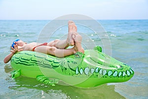 BOY SWIMS IN THE SEA ON INFLATABLE CROCODYLE TOY