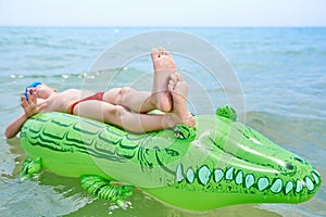 BOY SWIMS IN THE SEA ON INFLATABLE CROCODYLE TOY