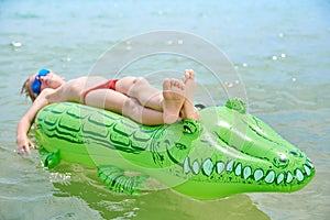 BOY SWIMS IN THE SEA ON THE INFLATABLE CROCODYLE TOY
