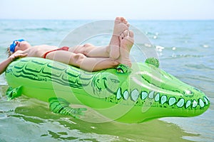 BOY SWIMS IN THE SEA ON THE INFLATABLE CROCODYLE TOY