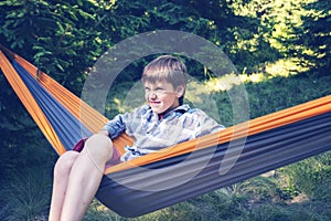 Boy is swinging in a hammock, with funny face