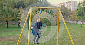 Boy swinging on swing, child having fun playing in outdoor public playground