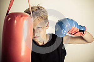 Boy swings single gloved hand at red punching bag