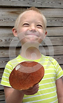Boy with syndrome down holding orange mushroom.