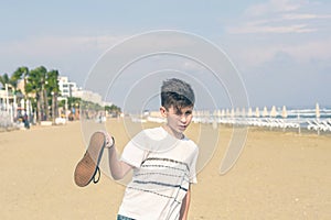 A boy in a T-shirt with sneakers on the sandy Mackenzie beach in Larnaca. Cyprus
