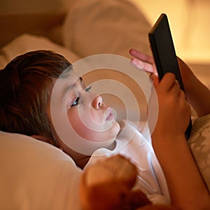 Boy, tablet and bed with night, learning and relaxing for social media or learning. Child, bedroom and connectivity for