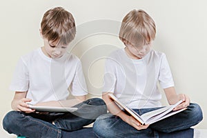 Boy with tablet computer and kid reading a book. Kids education leisure concept.