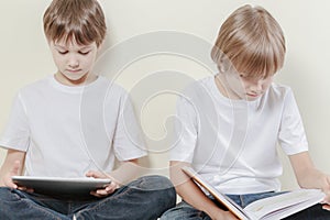 Boy with tablet computer and kid reading a book. Kids education leisure concept.