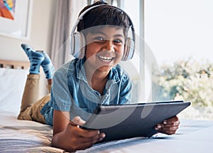 Boy, tablet and headphones on bed, portrait or smile for streaming subscription, movie or video to relax. Male child
