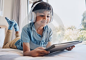 Boy, tablet and headphones on bed, reading of smile for streaming subscription, movie or relax with video. Male child