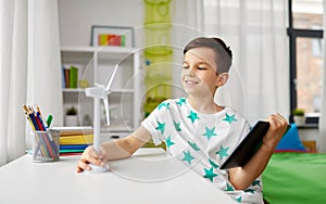 Boy with tablet and model of wind turbine at home