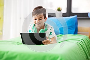 Boy with tablet pc computer playing game at home