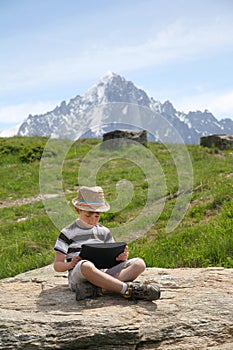 Boy with tablet PC sit on stone