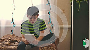 Boy tablet playing game browsing internet sitting on the couch