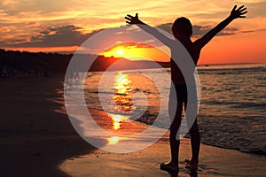 Boy takes a deep breath at the fiery sunset on the sea photo