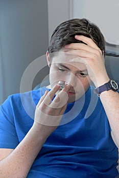 Boy takes his temperature with a clinical thermometer