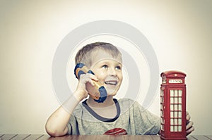 Boy talking on the phone and red telephone booth