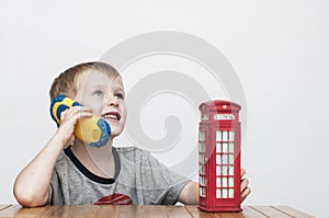 Boy talking on the phone and red telephone booth