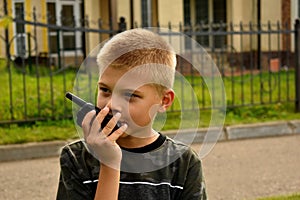 The boy is talking on the walkie-talkie. Boyish war games