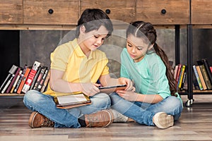 Boy teaching focused girl how to use digital tablets