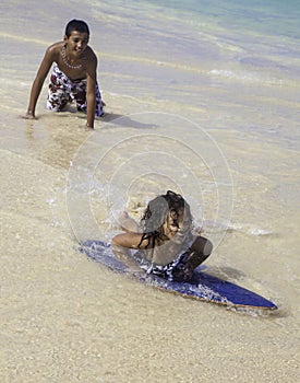 Boy teaching sister to skim board