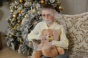 boy with a teddy bear at a Christmas tree
