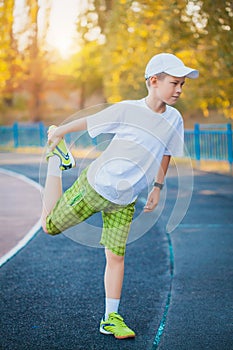 Boy Teen doing sports exercises on a stadium