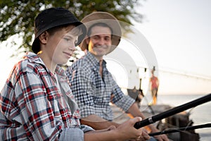 boy teen and his father fishing together from a pier.