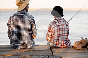 boy teen and his father fishing together from a pier, back view