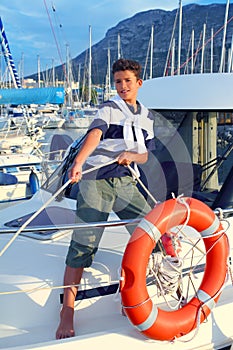 Boy teen sailor mooring boat rope in harbor photo