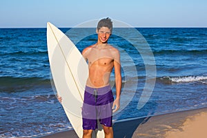 Boy teen surfer happy holing surfboard on the beach