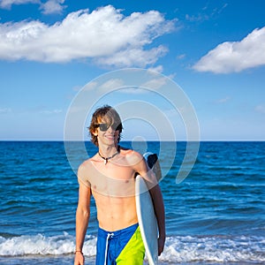 Boy teen surfer happy holing surfboard on the beach