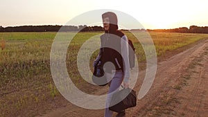 Boy teen traveling. Boy teenage tramp walking along the road in a hood with backpacks a sad traveler