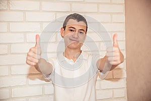 Boy teen in white t-shirt shows thumb up