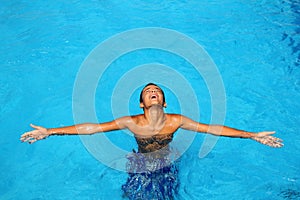 Boy teenage relaxed open arms blue swimming pool