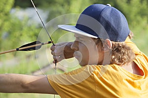 Boy teenager archer aiming arrow