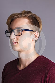 Boy teenager in glasses poses in grey studio