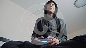 Boy teenager in the hood playing video games on the console on the gamepad. Young teen Man hooded sweater Absorbed In