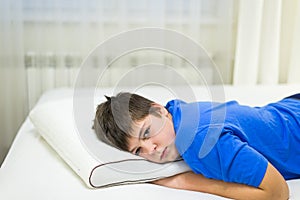 Boy teenager lying face down on anatomic pillow